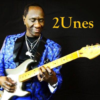 Musician in a blue jacket playing an electric guitar.