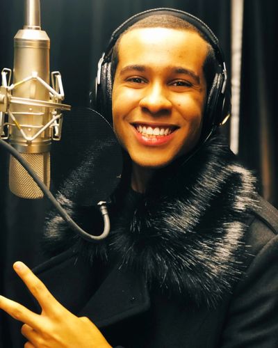 Smiling young man in headphones recording music in studio.