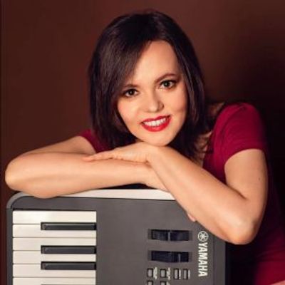 Woman smiling while leaning on a Yamaha keyboard.