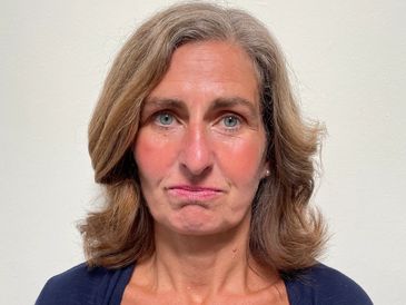 A middle-aged woman with shoulder-length hair looks concerned.