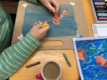 Person drawing a colorful anatomical heart with pastels on paper.