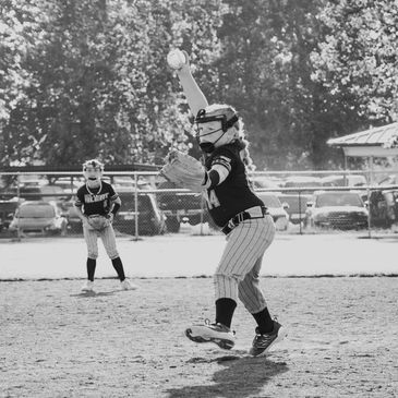 Young softball pitcher in mid-throw during a game.