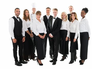 Group of restaurant staff in uniforms posing together.