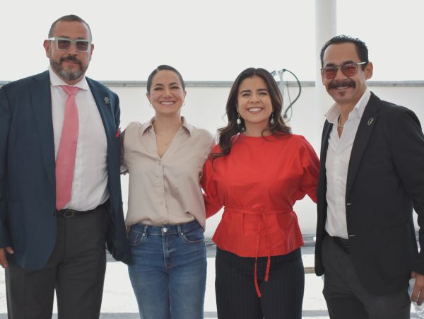 Cuatro personas sonrientes posan juntas en un evento.