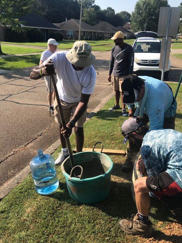 Group of men mixing cement outdoors on a sunny day.