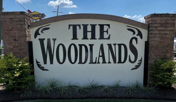 Entrance sign for The Woodlands community with decorative brick pillars.