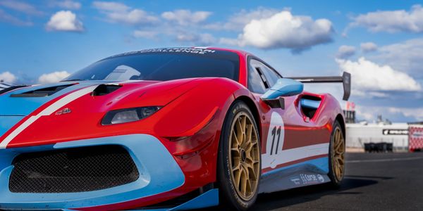Red and blue race car with number 11 on track under a blue sky.