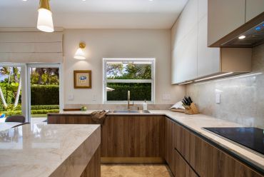 Modern kitchen with wooden cabinets and marble countertops.