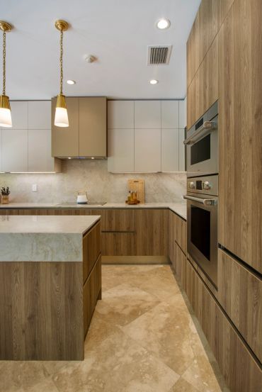 Modern kitchen with wood cabinets, marble countertops, and pendant lights.
