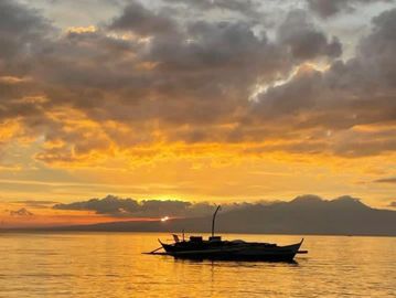 Boat silhouetted against a vibrant sunset.