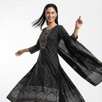 Woman twirling in a black patterned traditional dress.