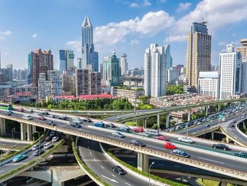 Busy multi-level highway interchange in a modern city with skyscrapers.
