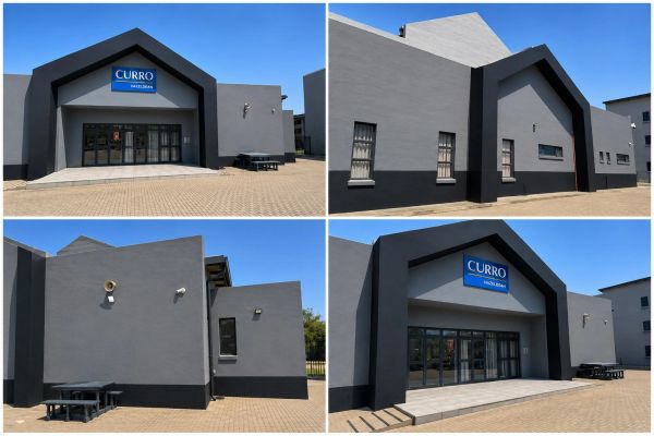 Modern gray building with blue Curro sign under clear blue sky.