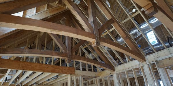 Exposed wooden beams and framing in a house under construction.