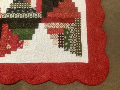 Close-up of a festive quilt corner with red scalloped border and intricate patterns.