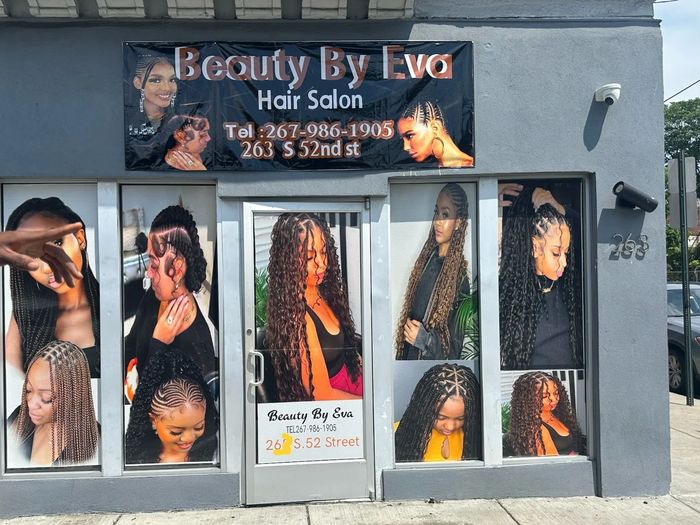 Beauty By Eva hair salon showcases diverse braided and curly hairstyles on its storefront.