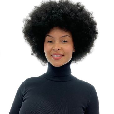 Smiling woman with a large afro wearing a black turtleneck.
