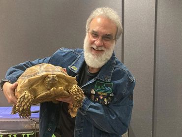 Man holding a turtle and smiling.