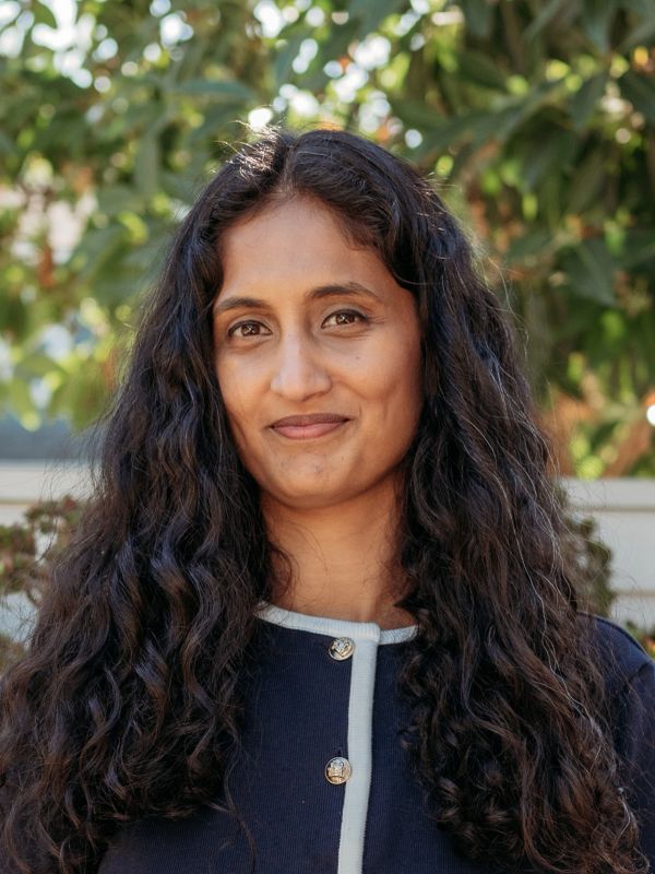 Woman with long curly hair smiles softly.