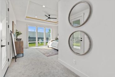 Modern bedroom with round mirrors and large windows.