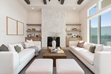 Modern living room with stone fireplace and white sofas.