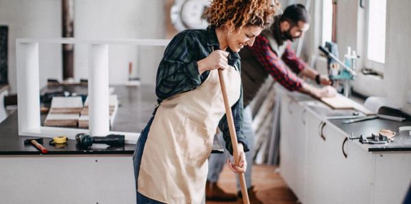 A man and a woman cleaning a kitchen after construction work.