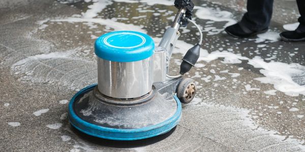 A roto machine being passed over a concrete floor.