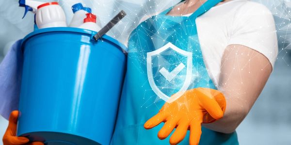 A woman carrying a bucket of cleaning supplies and gesturing to a checkmark badge.