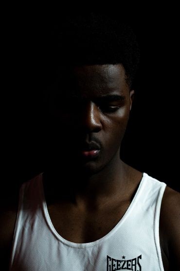 Portrait of a man in low light wearing a white tank top.