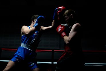 Two boxers in a dramatic, low-lit match with red and blue gloves.