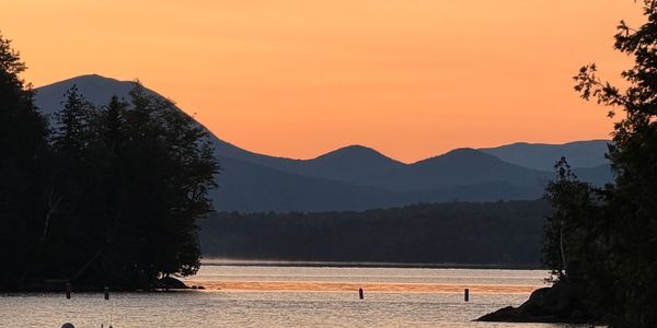 Sunset over a calm lake with mountains in the background.