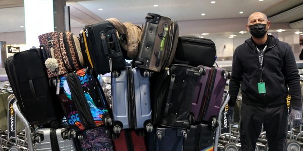 a man standing next to a cart filled with luggage