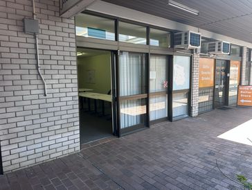 A quiet storefront with glass doors and signs for a gifts and dollar store.