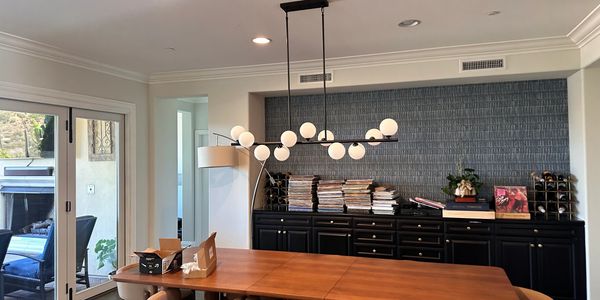 Modern dining room with wooden table, beige chairs, and unique chandelier.