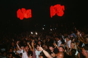 Crowd enjoying a concert or event with hands raised.