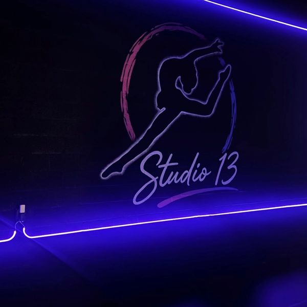Neon-lit wall art of a dancer at Studio 13.