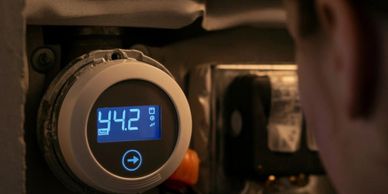 Person adjusting a digital thermostat displaying 44.2.