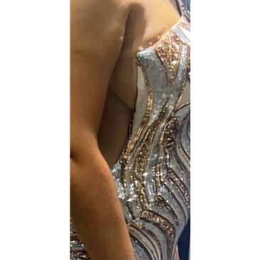 Close-up of a person's arm next to a sparkling, sequined dress.