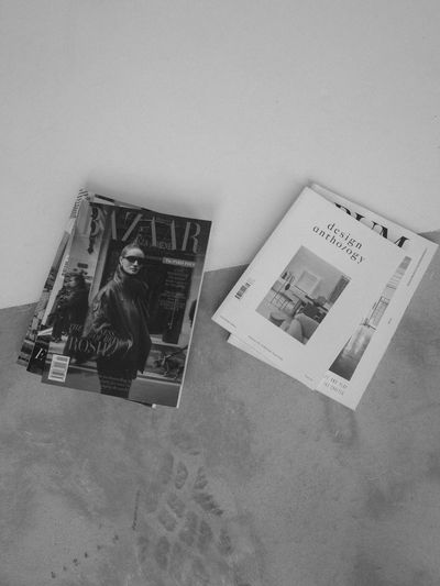 Two stacks of magazines on a textured floor with a diagonal line dividing light and dark areas.