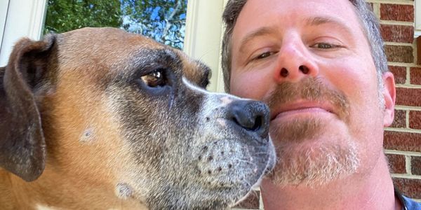 Close-up selfie of a man with his large dog looking sideways.