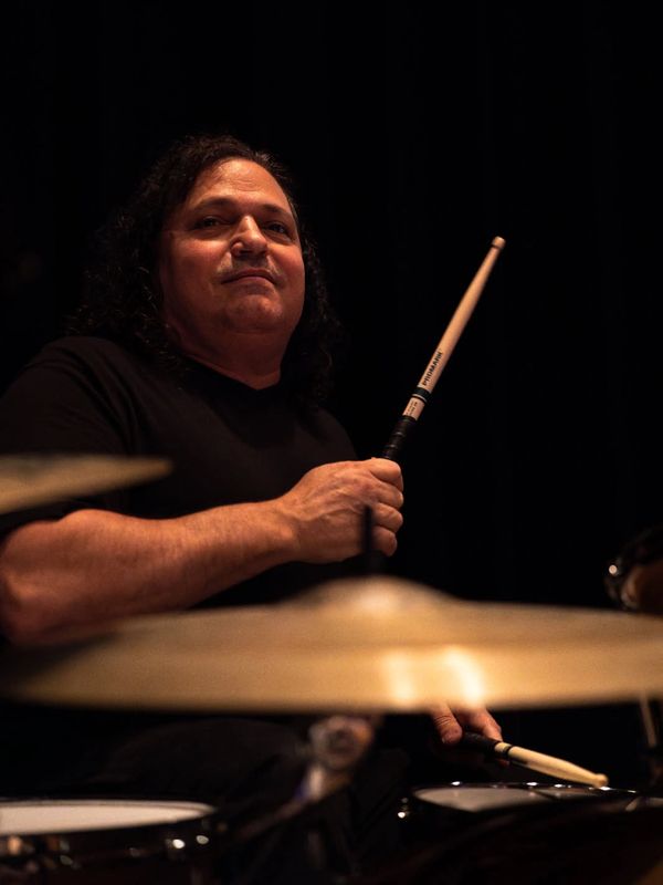 Musician holding drumsticks, poised to play drums.