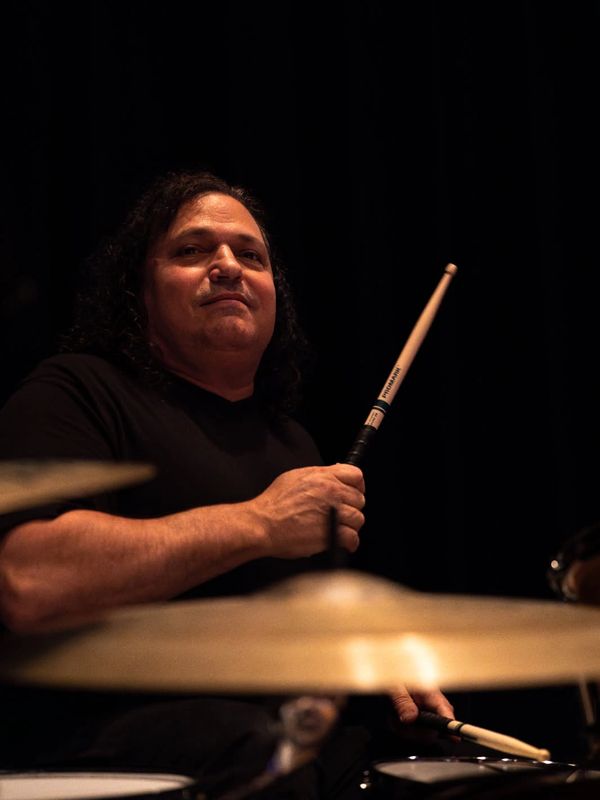 Musician holding drumsticks, poised to play drums.