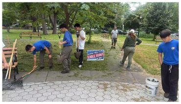 Group working on a park cleanup with tools and trash bags.
