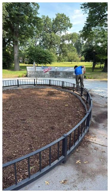 Man cleaning near a curved fence in a park.