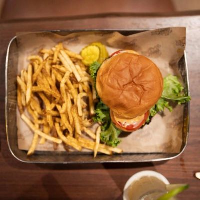Burger with fries and pickles on a tray.