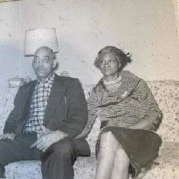 Vintage photo of a man and woman sitting on a couch in a modest room.