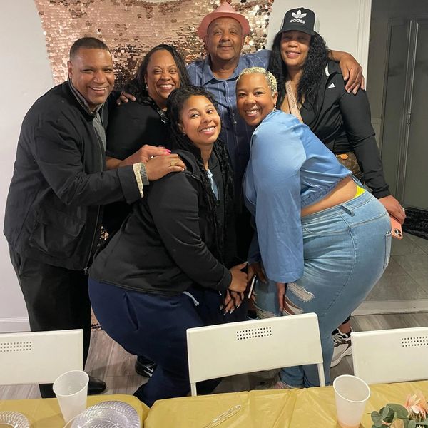 Six people smiling and posing together indoors at a casual gathering.