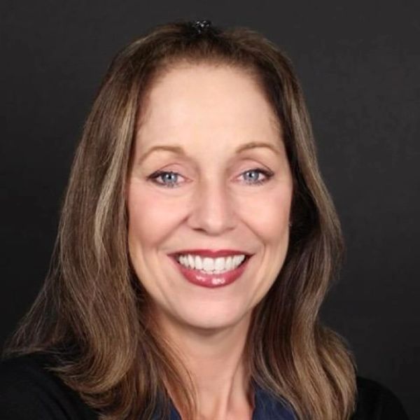 Smiling woman with long brown hair against a black background.
