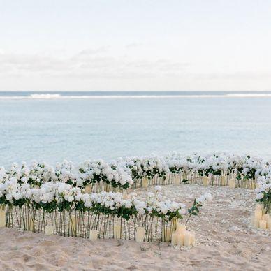 White flowers arranged by the calm ocean under a clear sky.