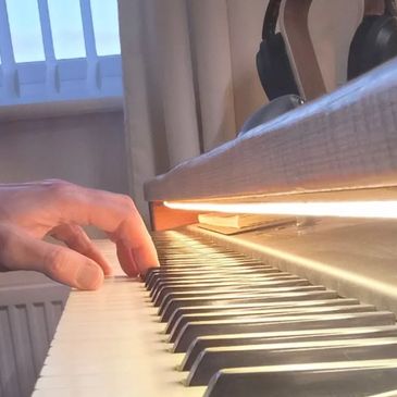 Hand playing piano keys under warm lighting.